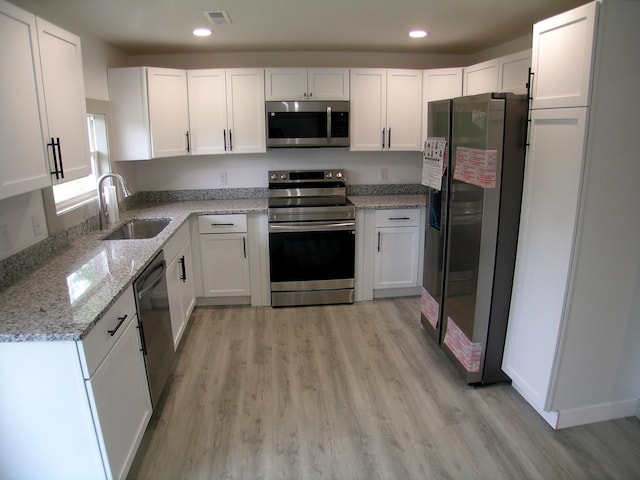 kitchen featuring a sink, appliances with stainless steel finishes, light wood-type flooring, and white cabinetry