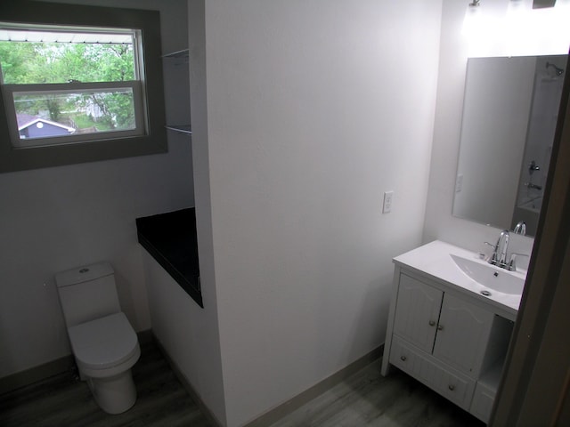 bathroom with vanity, baseboards, wood finished floors, and toilet