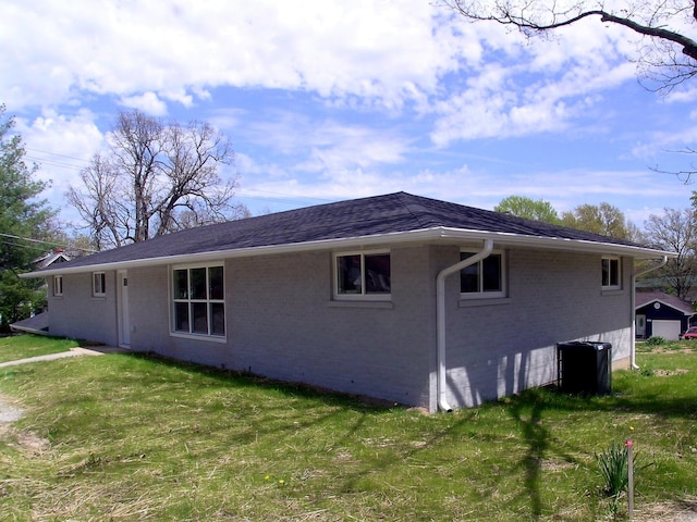 view of side of property featuring a lawn, brick siding, and central air condition unit