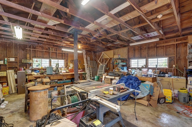 miscellaneous room featuring concrete flooring, wood walls, and a workshop area