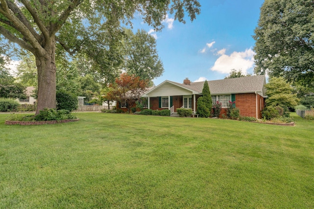 ranch-style house featuring a front lawn, brick siding, and a chimney