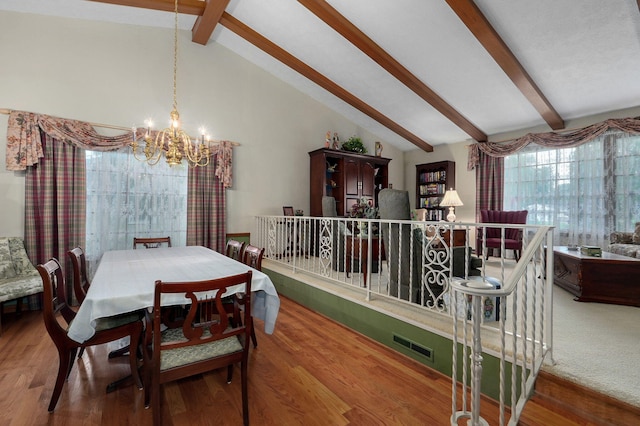 dining room with a chandelier, beam ceiling, wood finished floors, and high vaulted ceiling