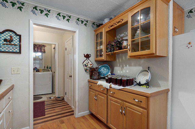 bar area with washer / clothes dryer, light wood-style flooring, freestanding refrigerator, and a textured ceiling