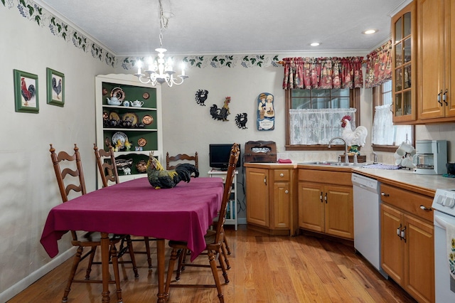 kitchen with white dishwasher, a chandelier, crown molding, light wood-type flooring, and a sink