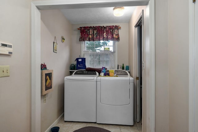 laundry area featuring separate washer and dryer, light tile patterned flooring, and baseboards