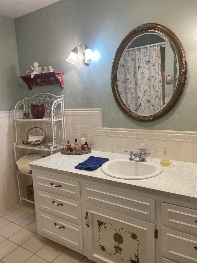 full bath featuring tile walls, vanity, tile patterned flooring, and a wainscoted wall