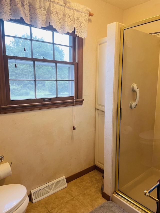 bathroom featuring a stall shower, toilet, and baseboards