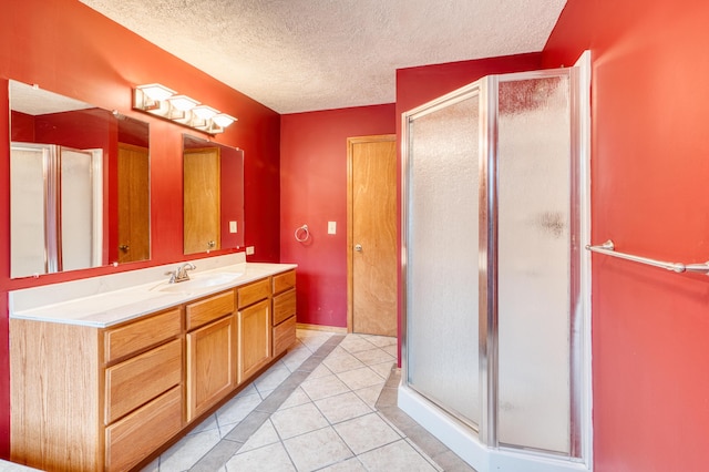 bathroom with tile patterned flooring, vanity, a textured ceiling, baseboards, and a shower stall