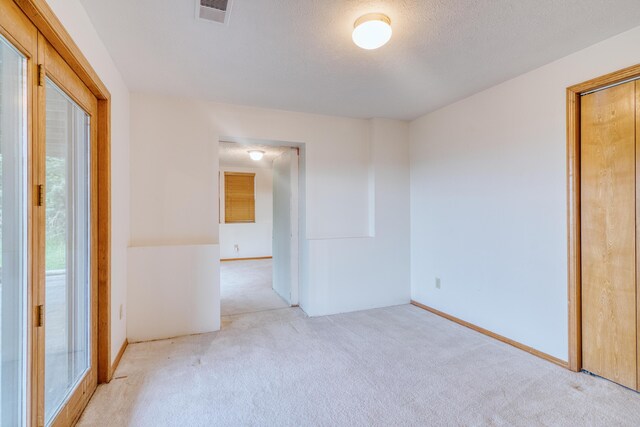 empty room featuring carpet flooring, visible vents, and a wealth of natural light