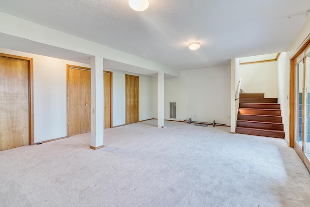 below grade area with stairway, light colored carpet, and visible vents