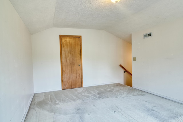 additional living space featuring baseboards, visible vents, light carpet, and lofted ceiling