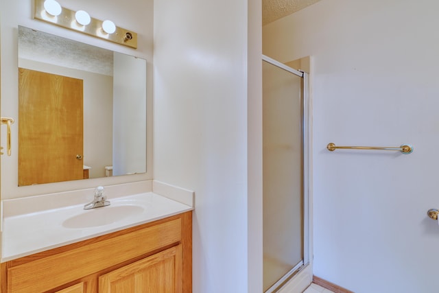full bathroom featuring vanity, a shower stall, toilet, and a textured ceiling