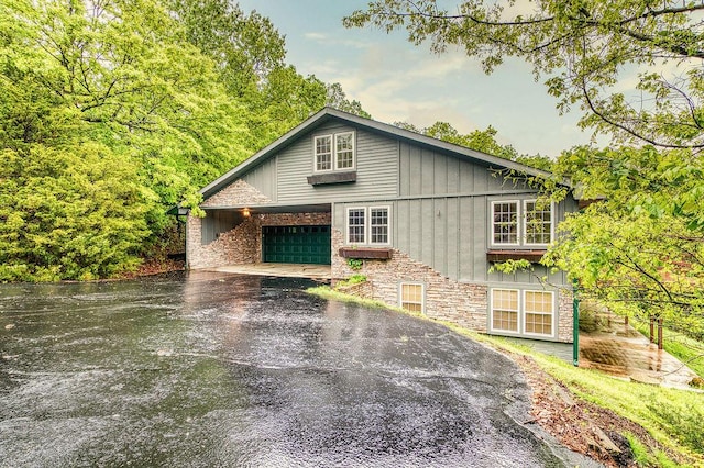 view of home's exterior with driveway, stone siding, and a garage