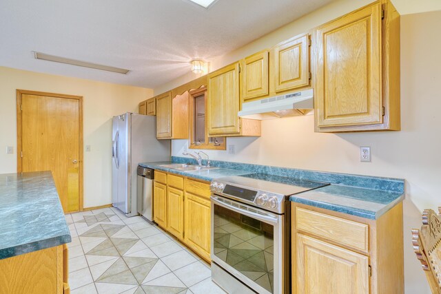kitchen with light brown cabinets, dark countertops, under cabinet range hood, a sink, and appliances with stainless steel finishes