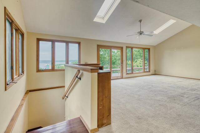 unfurnished living room featuring carpet floors, ceiling fan, and lofted ceiling with skylight