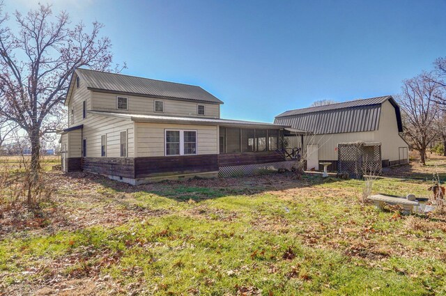back of house with a yard, a sunroom, and metal roof