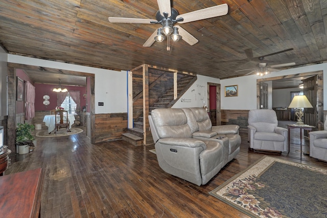 living area featuring wainscoting, wood-type flooring, ceiling fan with notable chandelier, stairs, and wood ceiling