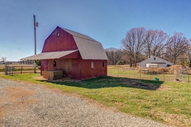 view of barn with a lawn and fence