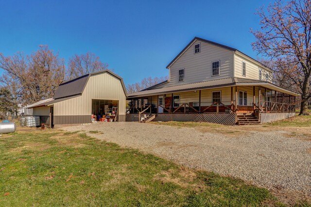 view of front facade with a barn, a garage, an outbuilding, covered porch, and gravel driveway