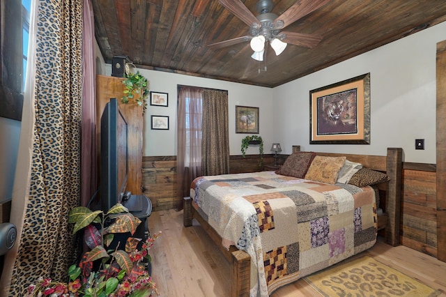 bedroom with wood ceiling, ceiling fan, wood finished floors, a wainscoted wall, and wooden walls