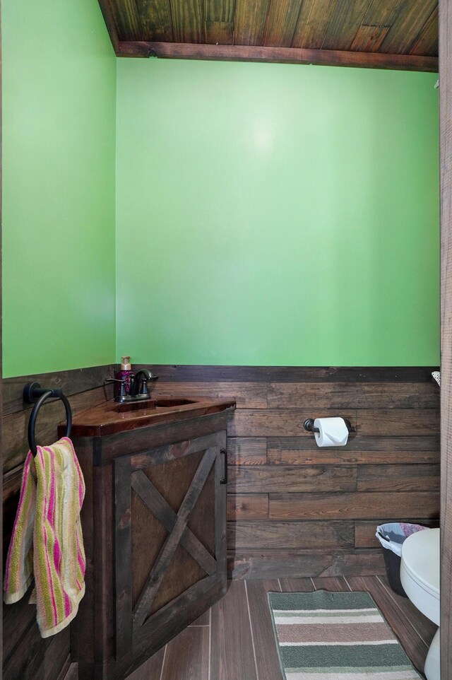bathroom featuring a sink, wooden ceiling, and toilet