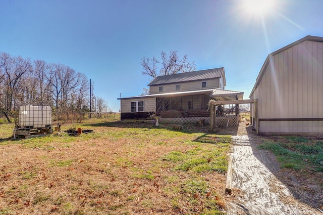 back of property featuring an outdoor structure and metal roof