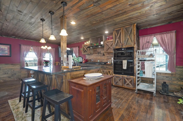 kitchen with dobule oven black, dark countertops, dark wood-type flooring, a center island, and wood ceiling