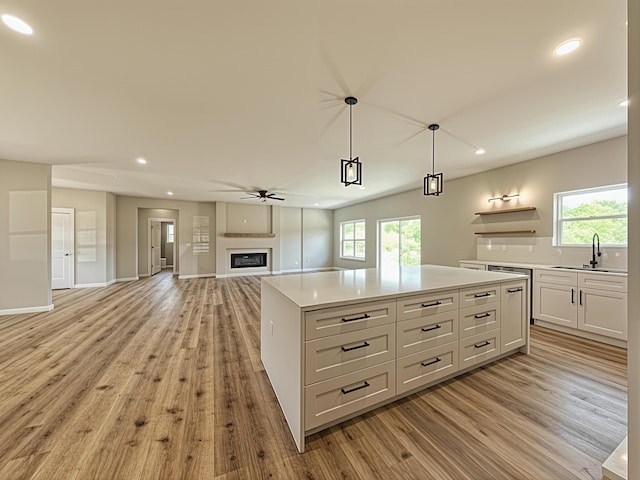3875 E Dehaven Ln, Fair Grove, MO 65648 - kitchen with light wood finished floors, recessed lighting, a glass covered fireplace, open floor plan, and white cabinetry