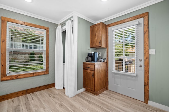 kitchen featuring brown cabinets, ornamental molding, baseboards, and light wood-type flooring