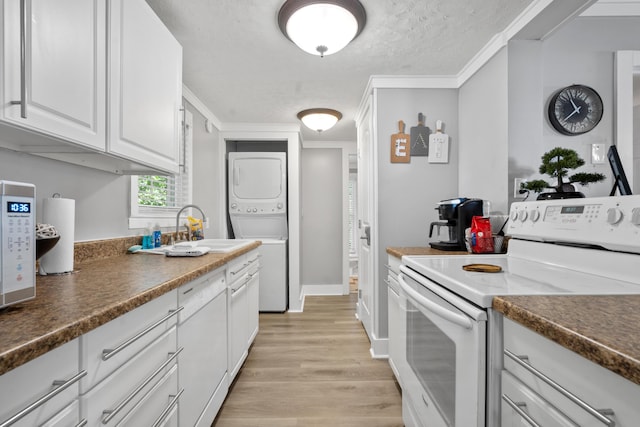 kitchen featuring white cabinets, a sink, light wood-style floors, white range with electric cooktop, and stacked washer and clothes dryer