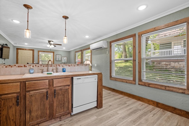 kitchen with crown molding, white dishwasher, a sink, an AC wall unit, and pendant lighting