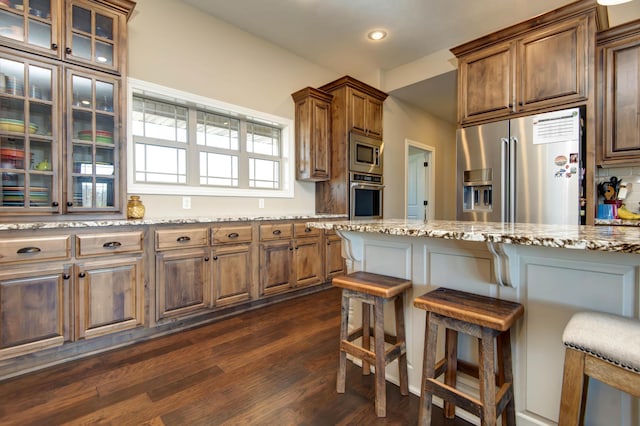 1770 Logan Ridge Rd, Ozark, MO 65721 - kitchen with light stone countertops, appliances with stainless steel finishes, a kitchen breakfast bar, recessed lighting, and dark wood-style floors