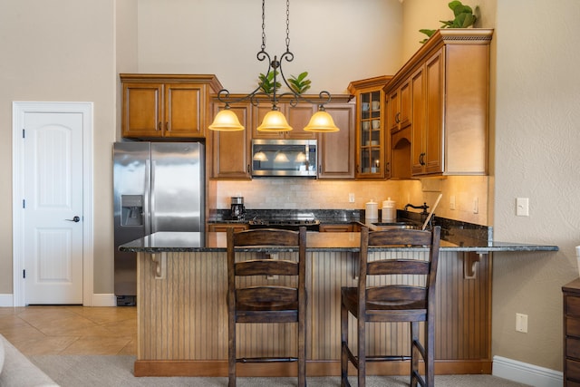 kitchen with brown cabinetry, a sink, backsplash, and stainless steel appliances