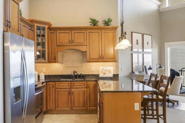 kitchen with a sink, appliances with stainless steel finishes, brown cabinetry, and a peninsula