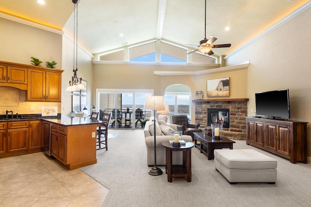 living room featuring crown molding, a glass covered fireplace, high vaulted ceiling, light colored carpet, and a ceiling fan