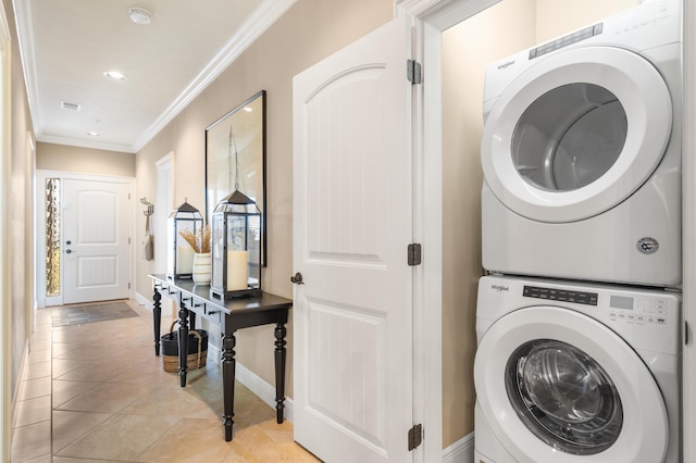 laundry room featuring laundry area, stacked washer and dryer, crown molding, light tile patterned floors, and baseboards