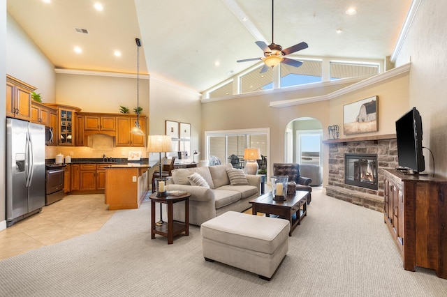 living room featuring ceiling fan, light colored carpet, a fireplace, arched walkways, and high vaulted ceiling