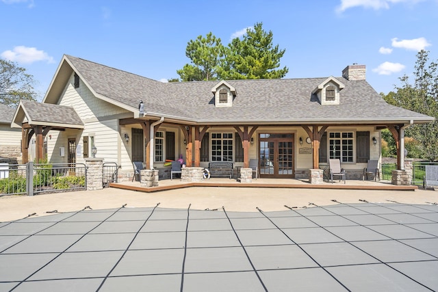 back of property with fence, roof with shingles, french doors, a chimney, and a covered pool