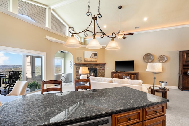 kitchen featuring visible vents, light colored carpet, a brick fireplace, open floor plan, and dark stone counters