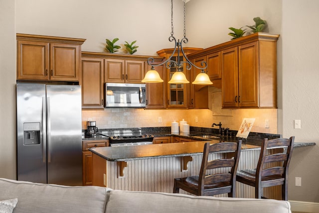 kitchen with brown cabinetry, a sink, tasteful backsplash, and stainless steel appliances