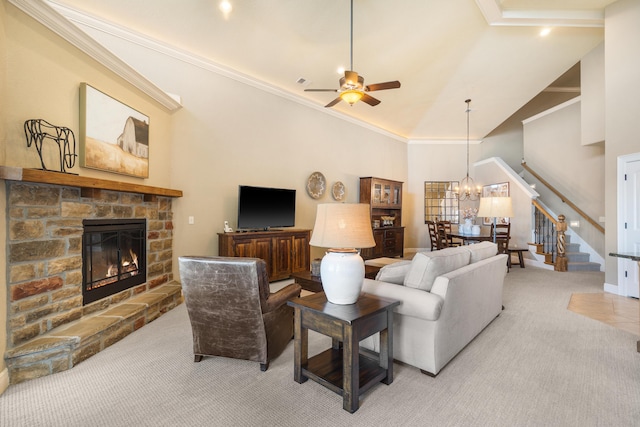 living area featuring a stone fireplace, light colored carpet, stairway, high vaulted ceiling, and ceiling fan with notable chandelier
