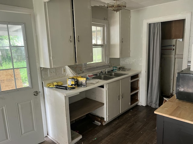 kitchen with light countertops, black microwave, a sink, and dark wood-type flooring