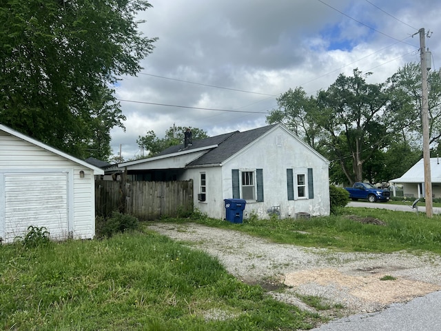 view of property exterior with stucco siding, dirt driveway, and fence