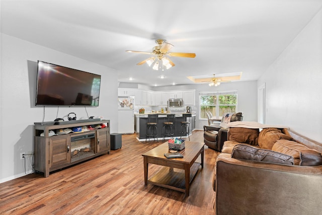 living room with a ceiling fan, a skylight, recessed lighting, and light wood finished floors