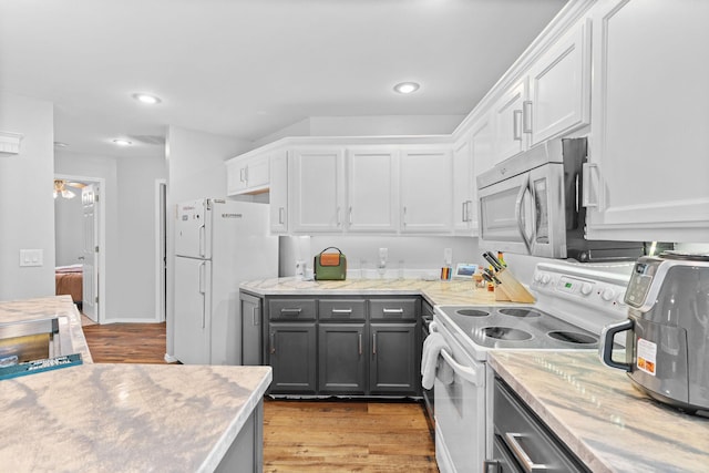 kitchen with white appliances, recessed lighting, white cabinets, and light wood-style floors