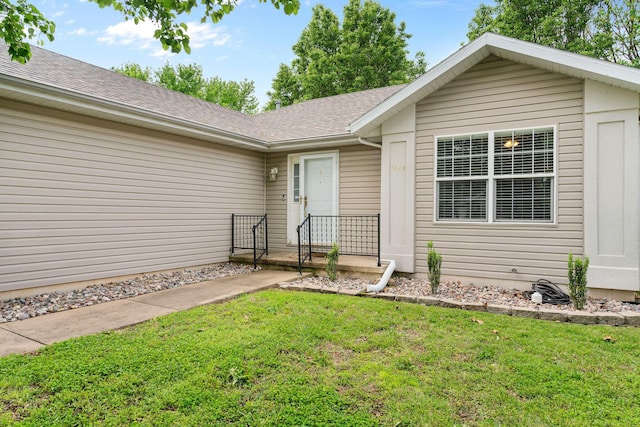 doorway to property with a yard and a shingled roof