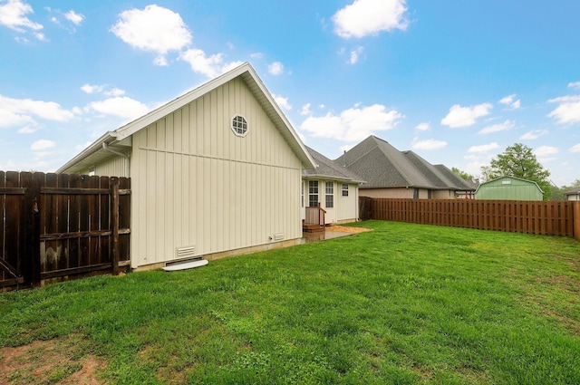 rear view of house featuring a lawn, a fenced backyard, and board and batten siding