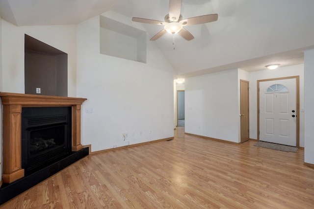 unfurnished living room with ceiling fan, light wood-style floors, a fireplace with raised hearth, high vaulted ceiling, and baseboards
