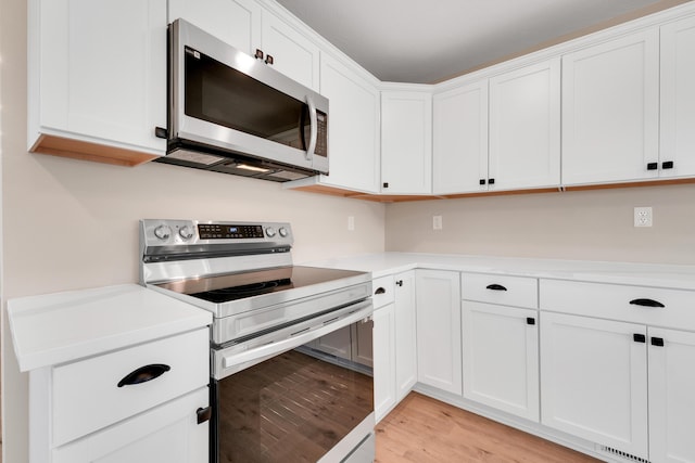 kitchen with light countertops, light wood finished floors, appliances with stainless steel finishes, and white cabinets