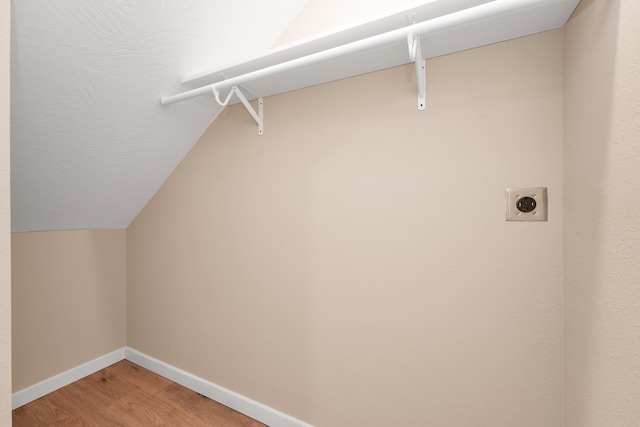 washroom with electric dryer hookup, laundry area, light wood finished floors, and baseboards